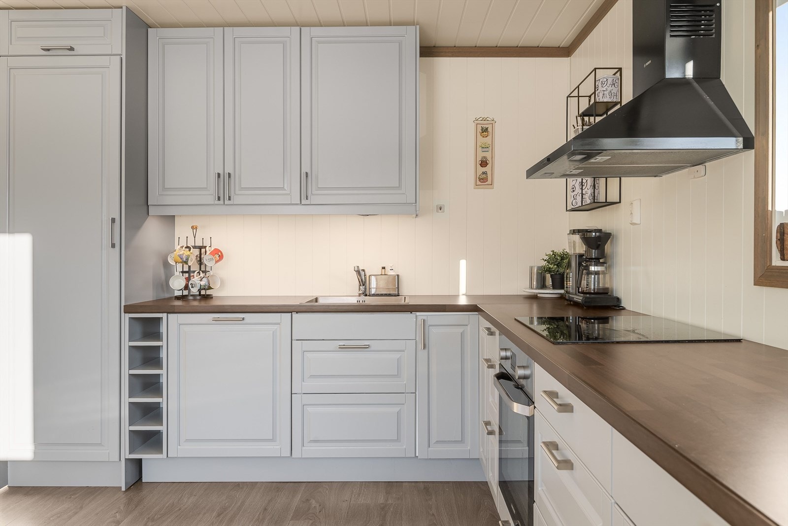 Det er godt med skap- og benkeplass på kjøkkenet som har en pent gråfarge og mørk benkeplate. Galleribilde