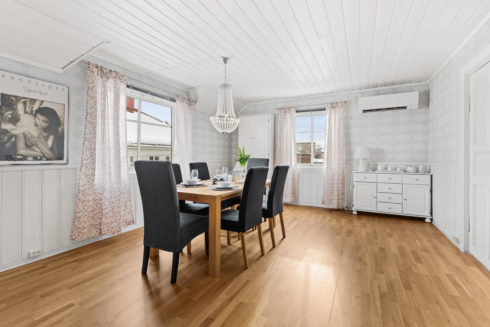 Lys og romslig stue/spisestue med 3-stavs parkettgulv, brystpanel og tapet på vegger og panel i himling med downlights Galleribilde