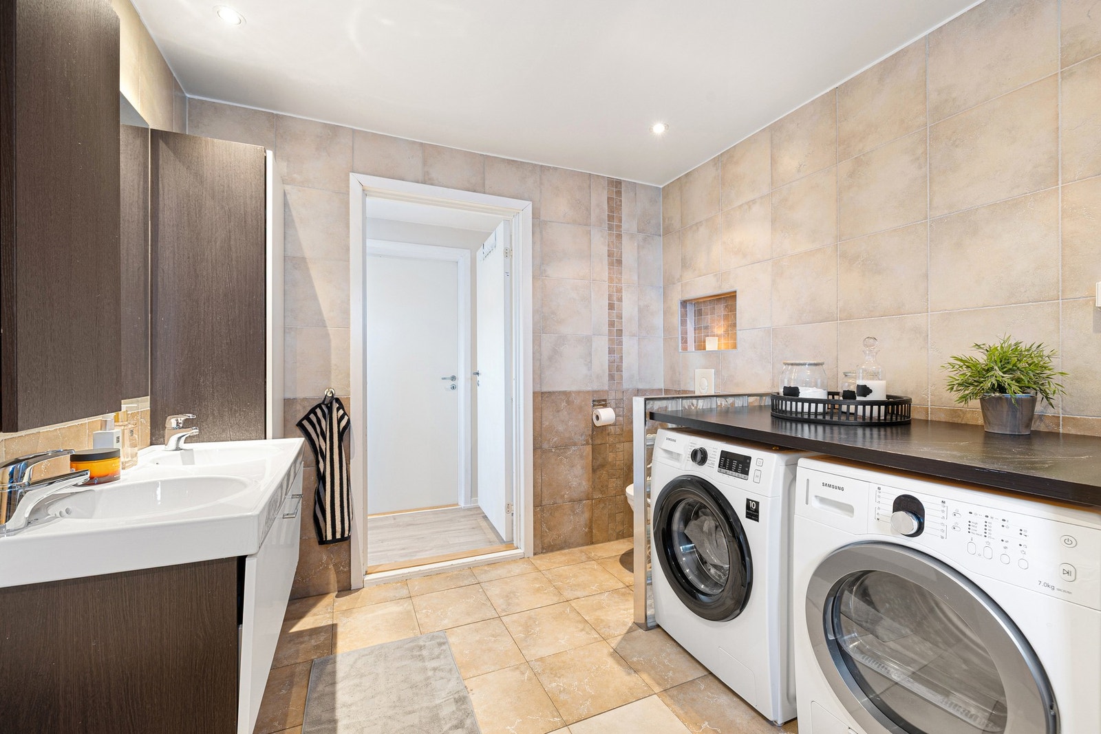 Badet er innredet med både badekar og dusjhjørne, i tillegg til opplegg for vaskemaskin og tørketrommel med god benkeplass. Galleribilde