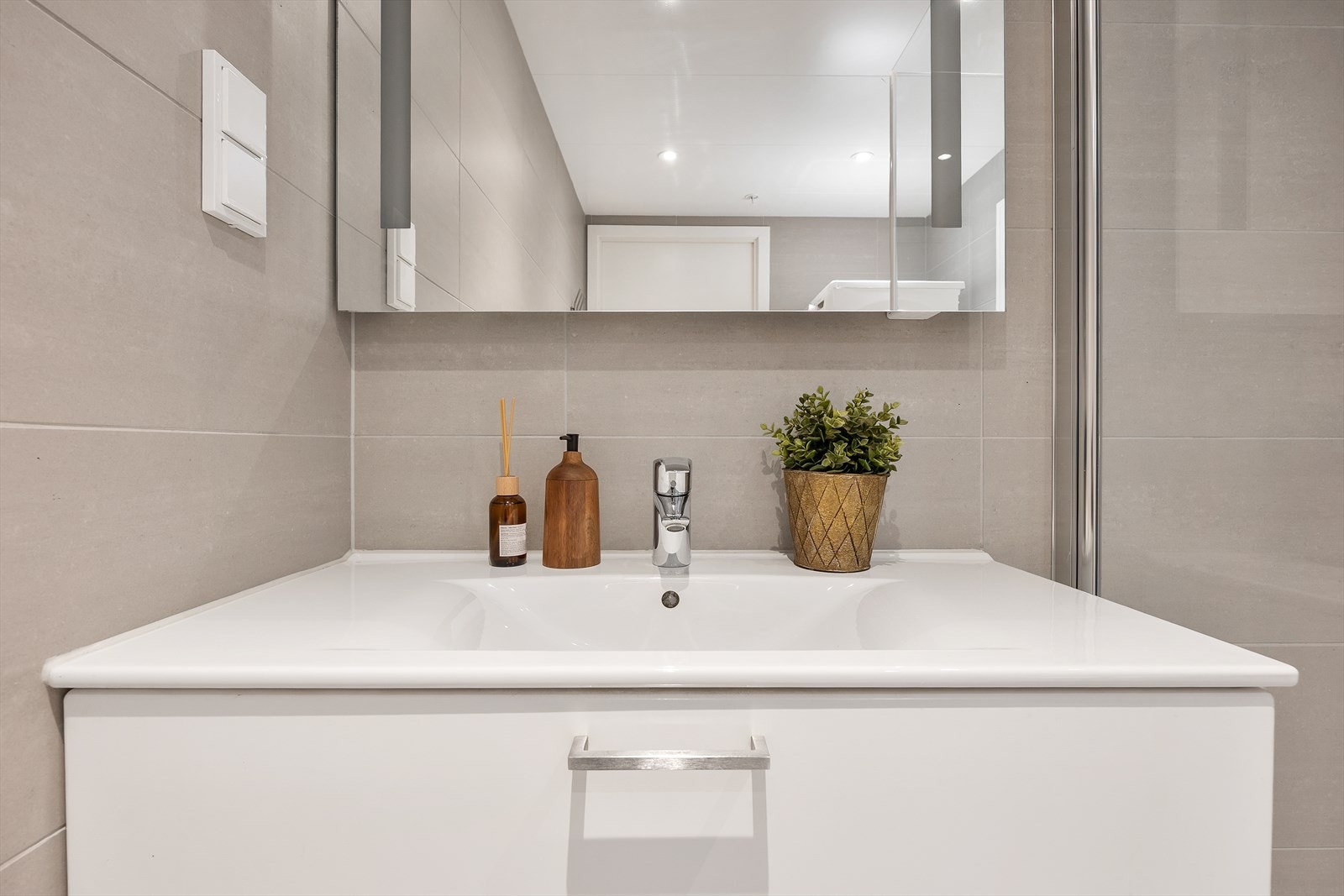 Baderomsinnredningen inkluderer speilskap med integrert belysning. Galleribilde