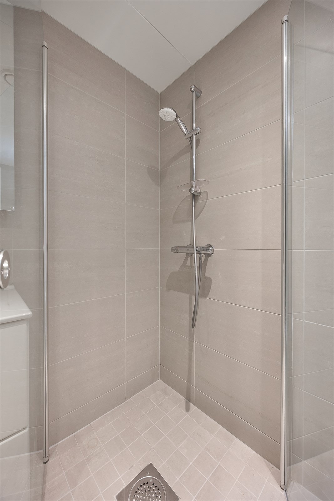 Dusjhjørne med innfellbare glassdører som frigjør gulvplass når dusjen ikke er i bruk. Galleribilde