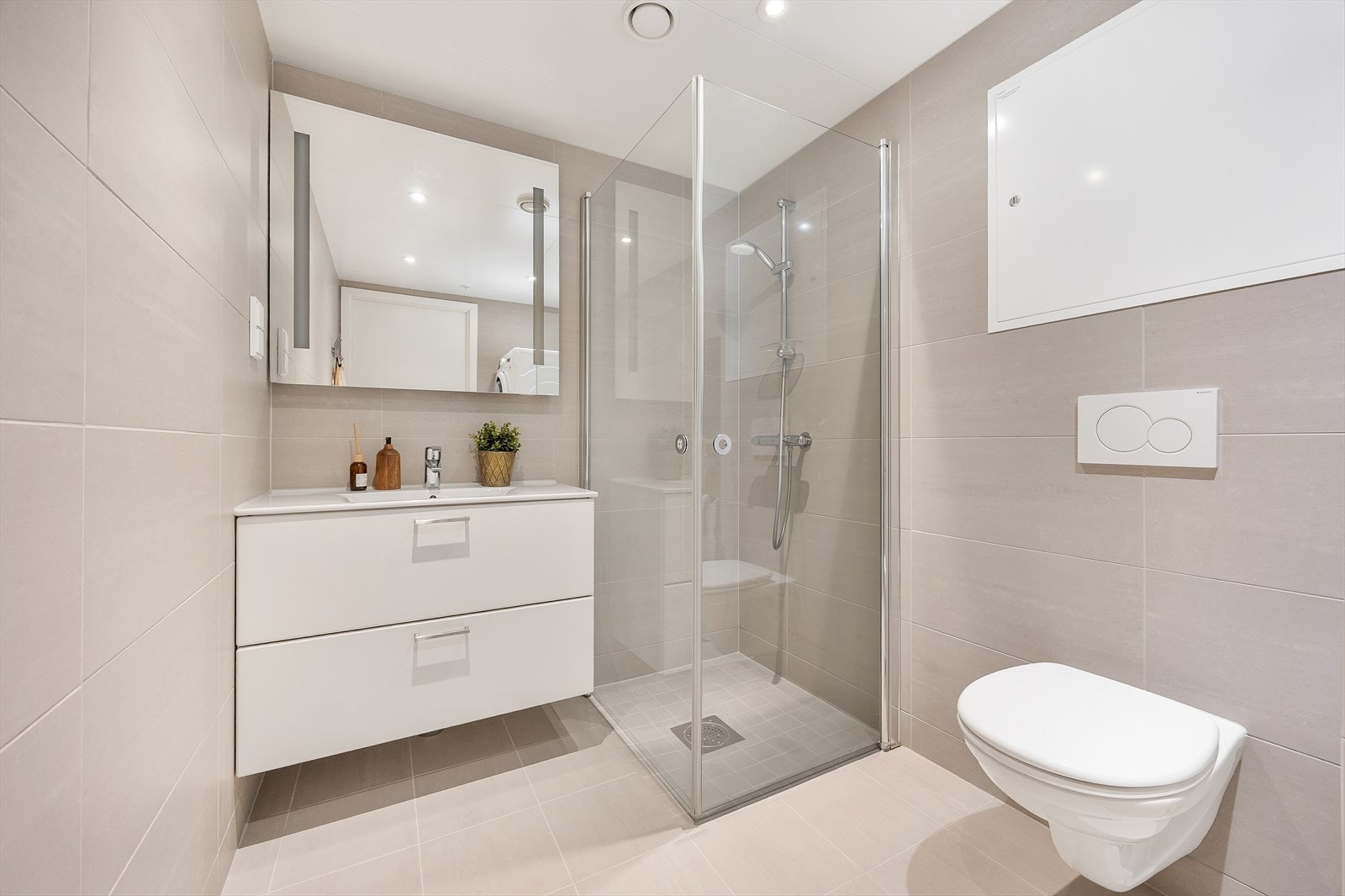 Delikat, flislagt bad med vegghengt toalett og servant med skuffeinnredning. Galleribilde