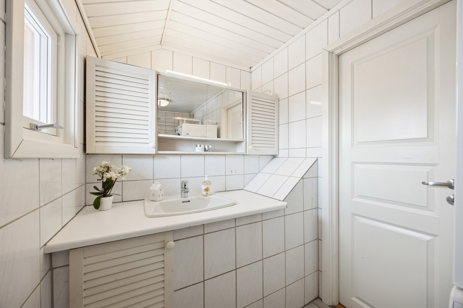 Badet er innredet med gulvstående toalett, dusjkabinett og servant. Galleribilde