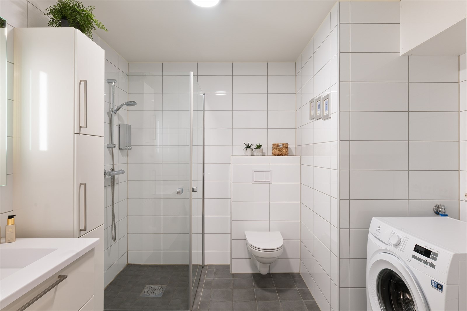 Fint bad med fliser på gulv og vegger, vegghengt toalett og dusjvegger som kan slås inn Galleribilde