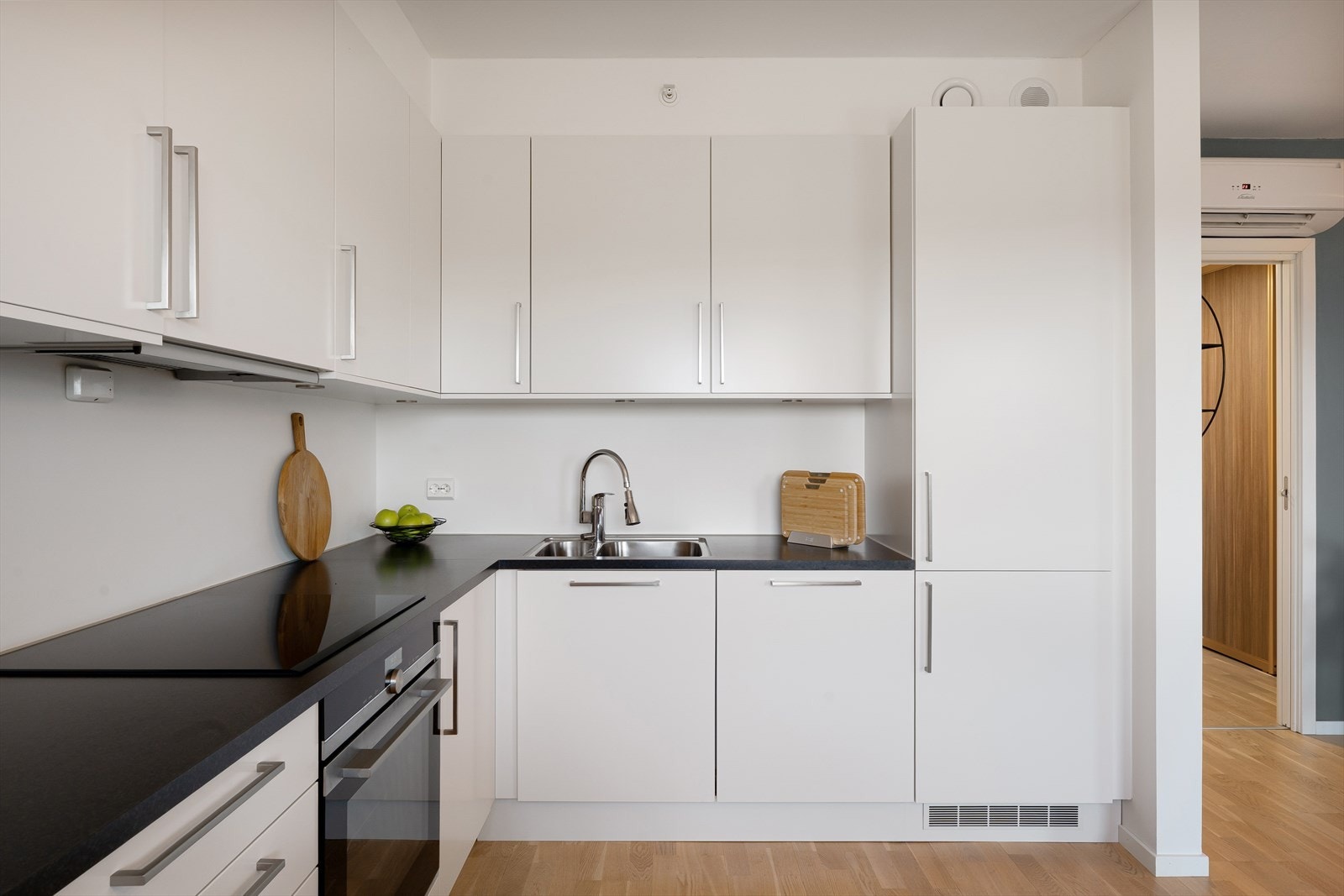 Kjøkkeninnredning i hvit slett utførelse og med mørk benkeplate Galleribilde