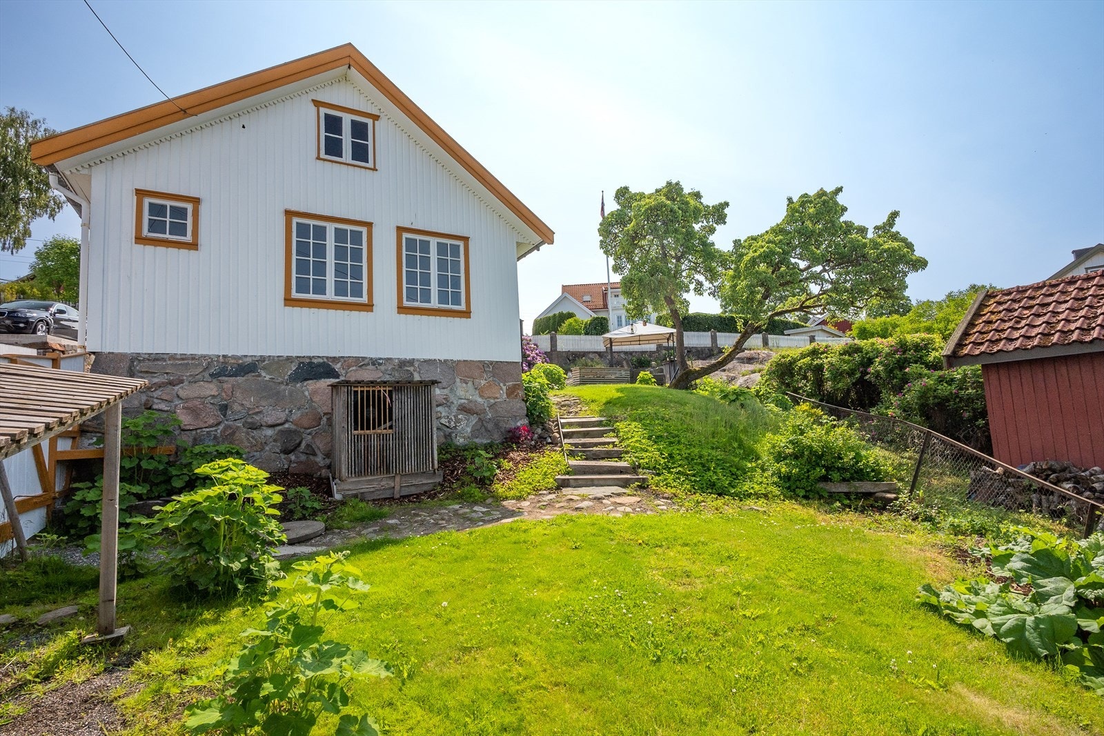 Tomten er opparbeidet med gressplen, hollandsk ballaststein, rhododendronbusk, div. bed og en hage full av stokkroser. Galleribilde