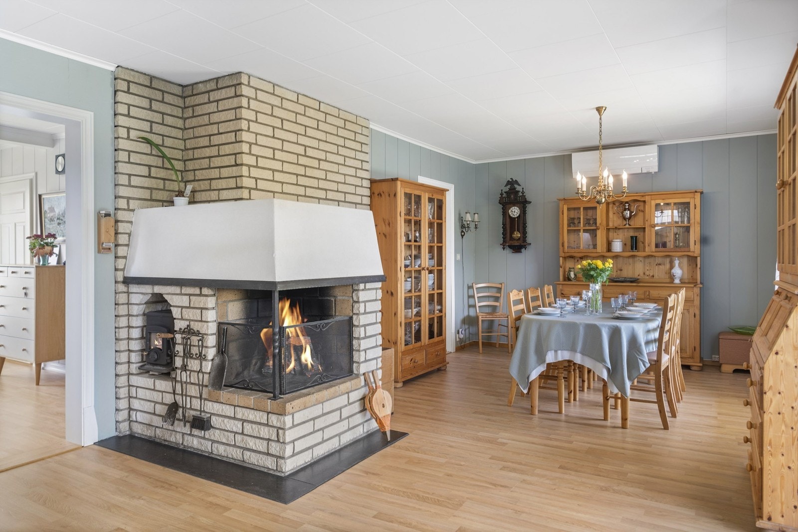 Stue med peis, spisebord, lyse vegger og tregulv. Romslig og lys atmosfære. Galleribilde