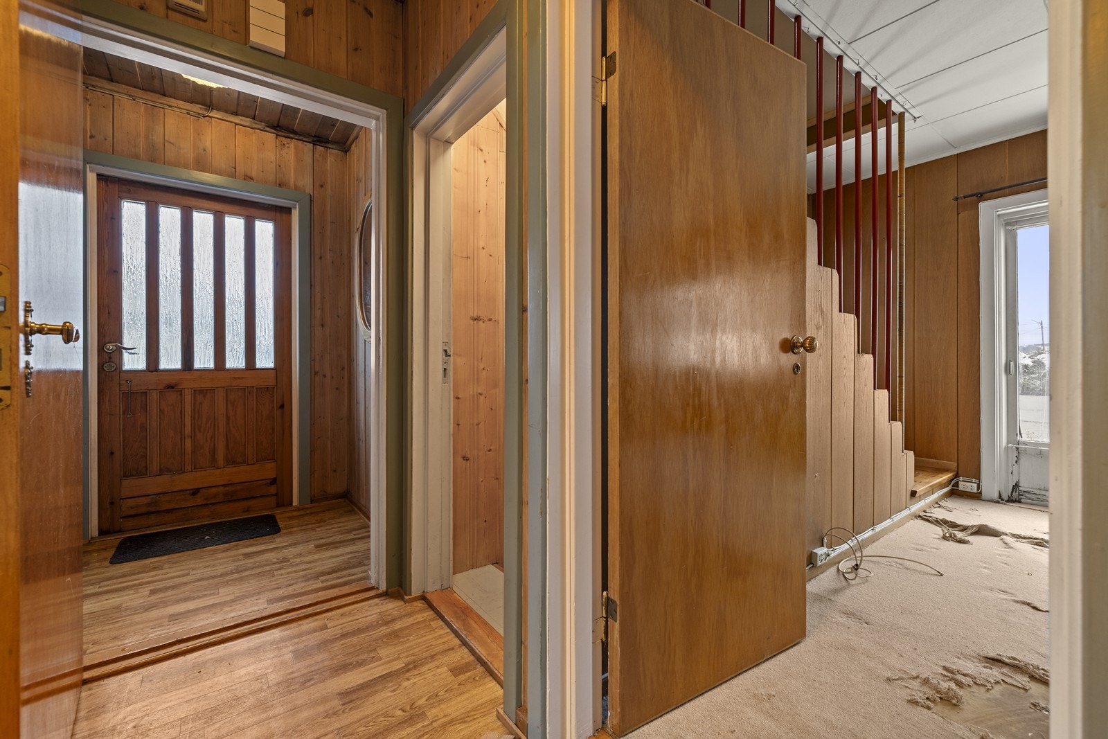 En lakkert tretrapp leder opp til andre etasje, mens en betongtrapp går ned til kjelleren. Galleribilde