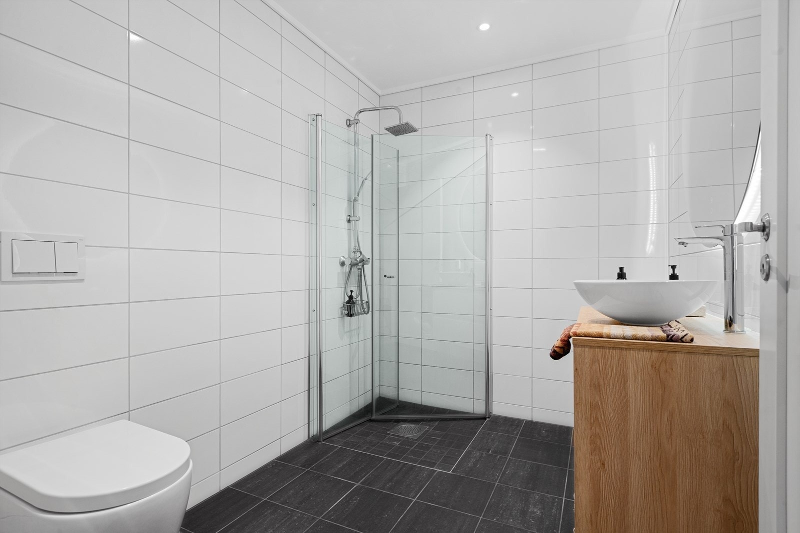 Videre finner du et dusjhjørne med innfellbare glassdører og vegghengt toalett. Galleribilde