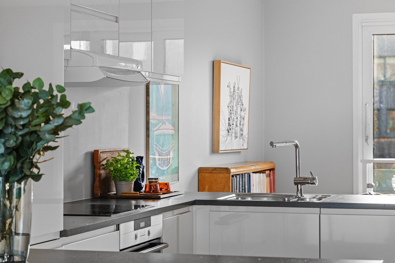 Kjøkkeninnredning fra HTH i tidløs hvit og integrerte hvitevarer, spotter under overskap og godt med benke - og skapplass. Galleribilde