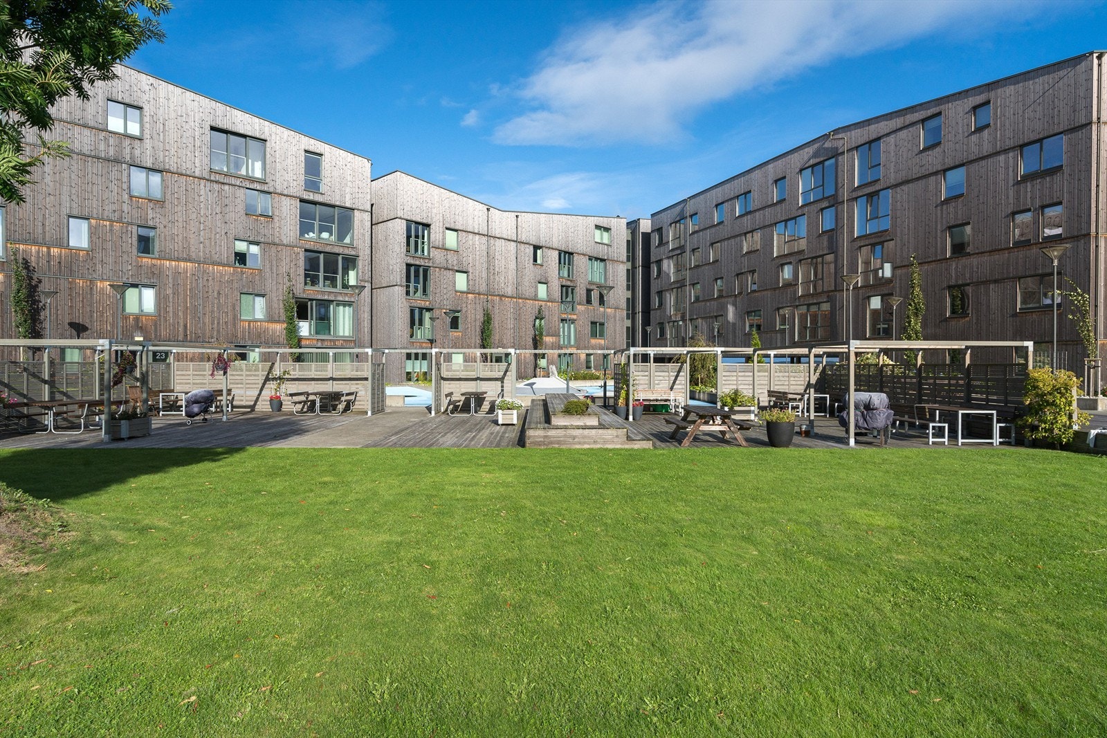 Solrikt fellesområder med benker, bord, grillplass, lekeplass m.m. Galleribilde