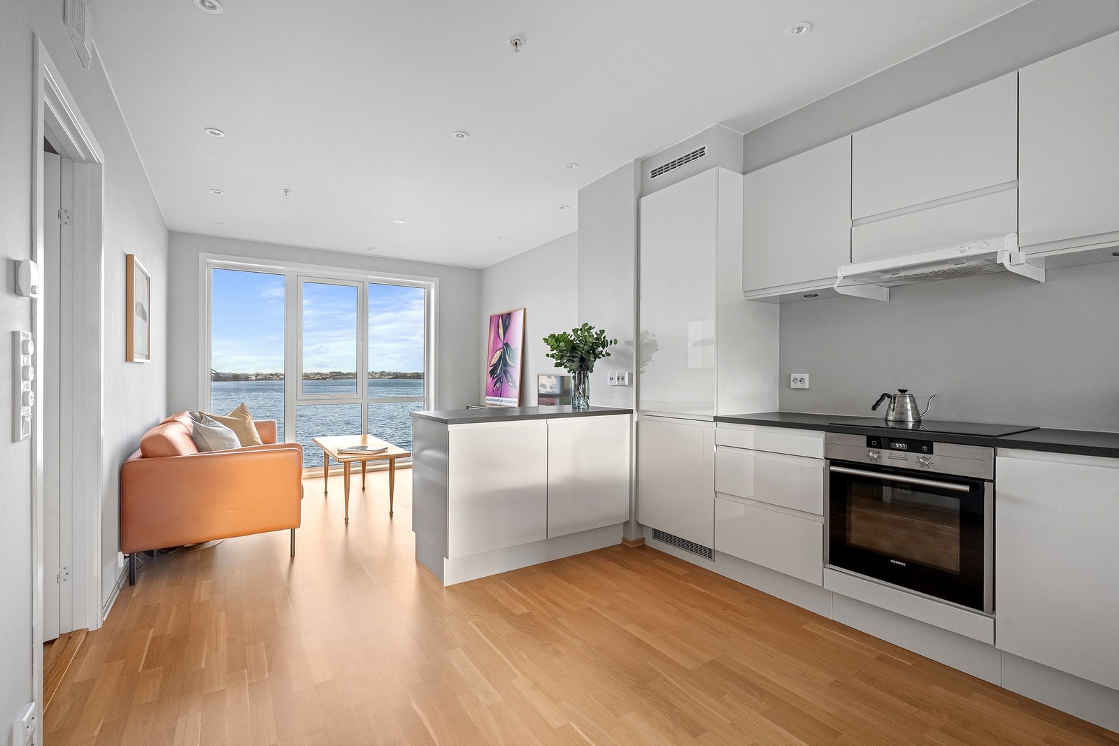 Fra entré kommer man inn til stue og kjøkken, som ligger i en åpen og sosial løsning. Her kjøkkenet plassert midt i rommet, slik t det er en naturlig avdeling mellom stue og spisestue, selv om man har det åpent. Galleribilde