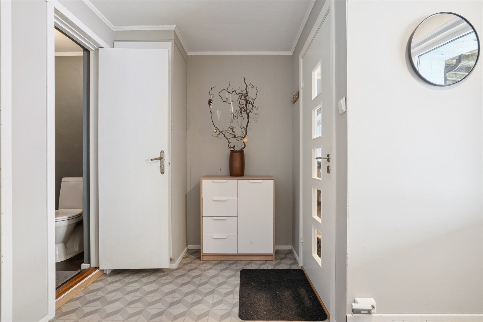 Inngangspartiet er funksjonelt utformet med flislagt vindfang (fliser fra 2024) og god plass til sko og yttertøy. Malt inngangsdør fra 2022 med glass og Yale doorman låskasse. Galleribilde