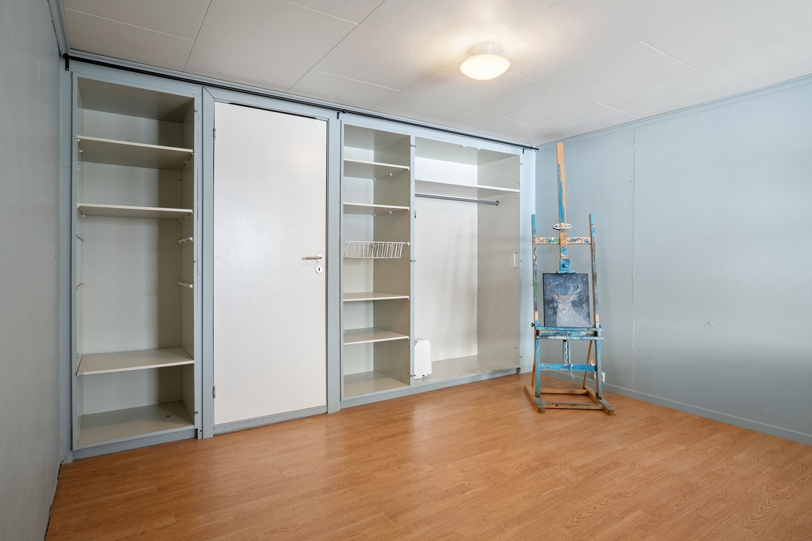 Rommet innredet som soverom har åpen garderobeløsning og videre adkomst til ett av boligens flere innvendige bod-rom. Galleribilde