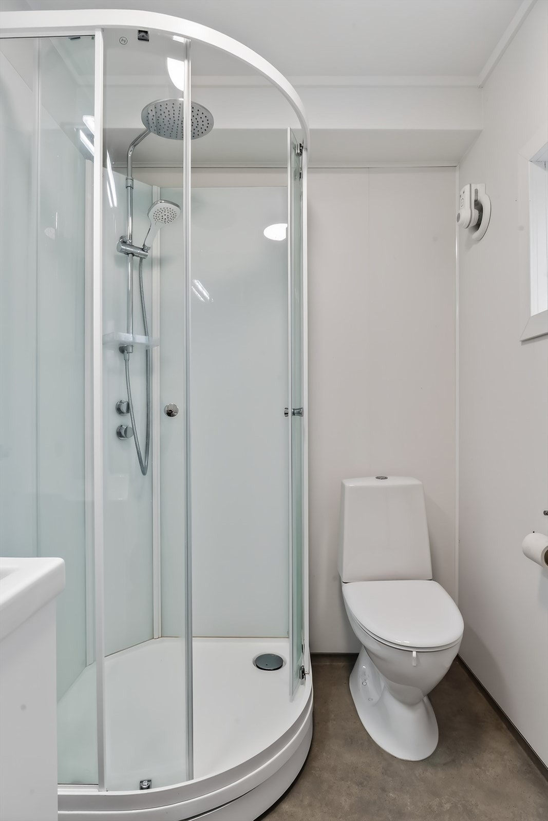 Rommet er utstyrt med praktisk dusjkabinett, gulvstående toalett og et lite vindu som gir naturlig lys og ventilasjon. Galleribilde