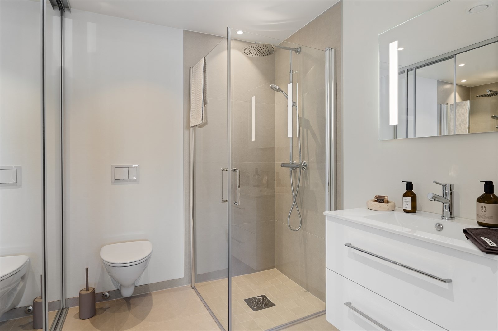 Pent bad/vaskerom med skyvedører foran opplegg for vaskemaskin Galleribilde