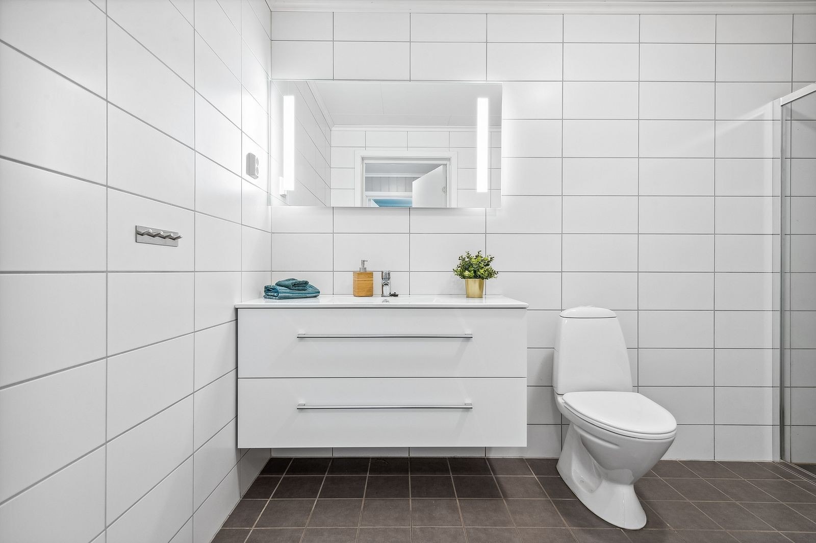 Baderommet er innredet med servant med skuffer under og speil med belysning. Galleribilde