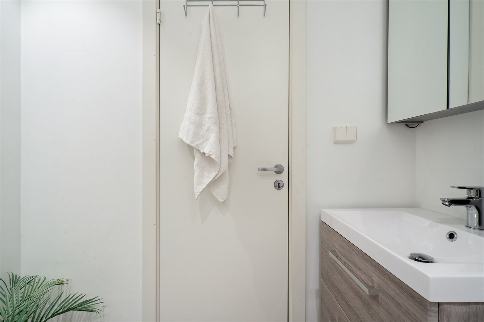 Innredningen består av en servant med skuffer, speilskap med stikkontakt, vegghengt toalett og svingbare dusjvegger i glass. Galleribilde