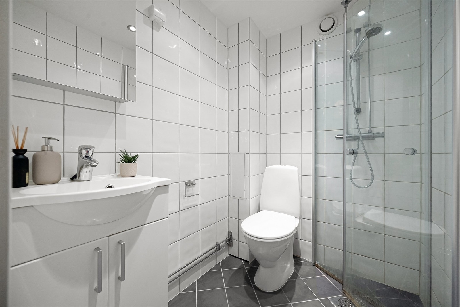 Flislagt bad med servantinnredning og dusj. Galleribilde