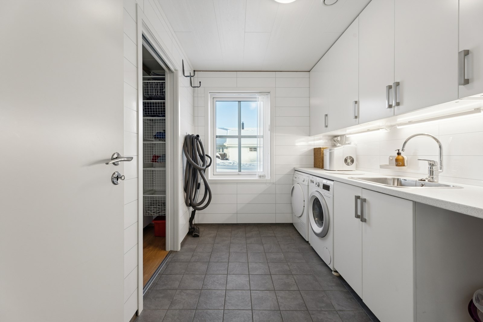 Praktisk vaskerom med smart vaskeromsinnredning og opplegg for vaskemaskin/tørketrommel. Varmekabler i gulv. Galleribilde