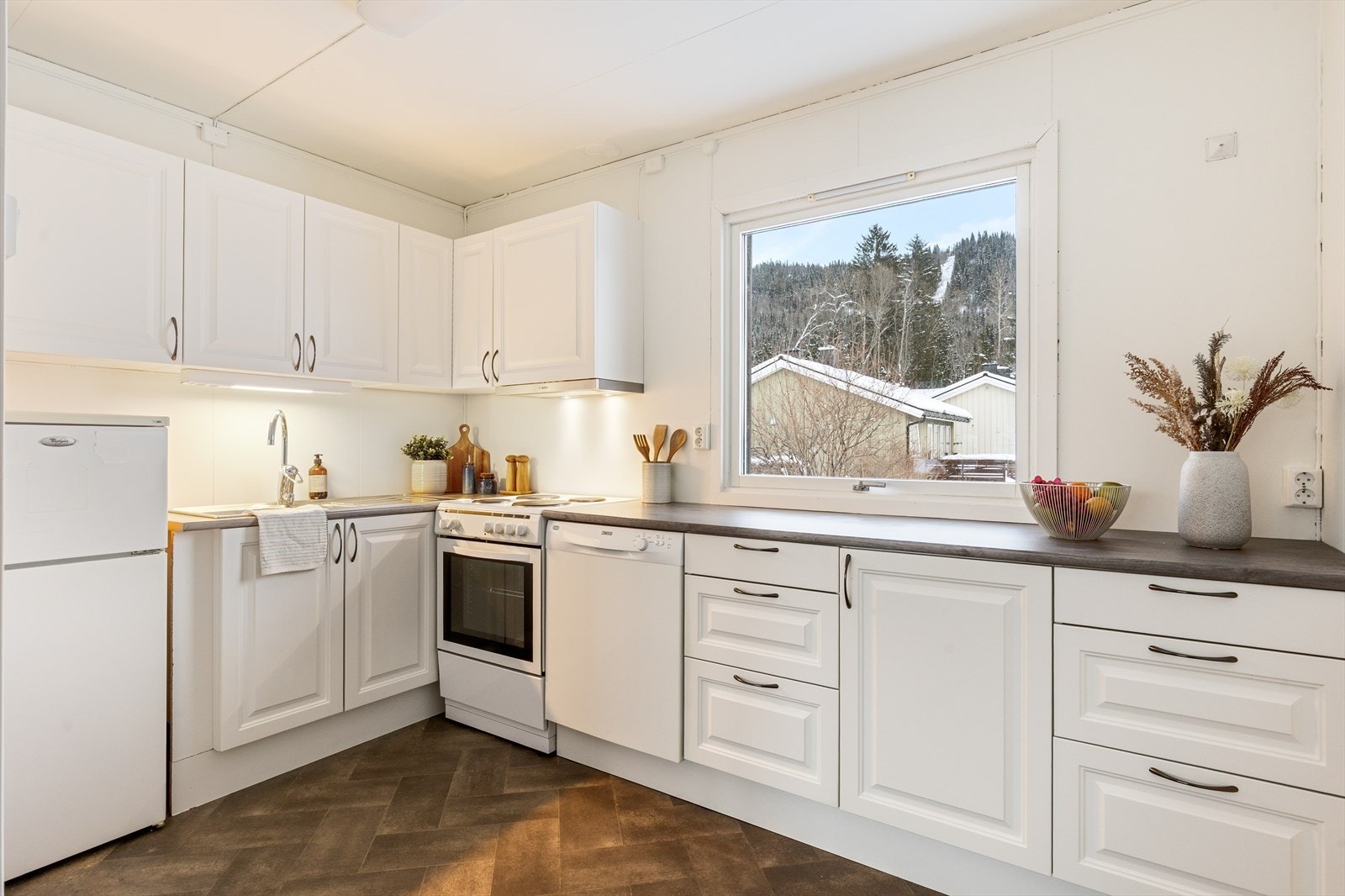 Lyst og tidløst kjøkken med alt en måtte trenge av skap-, skuff- og benkeplass. Galleribilde