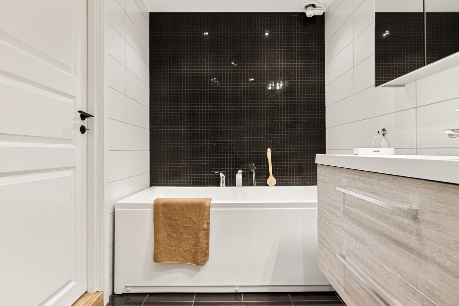 Badet er innredet med vegghengt toalett, servant med innredning, speilskap, dusjhjørne og badekar. Galleribilde