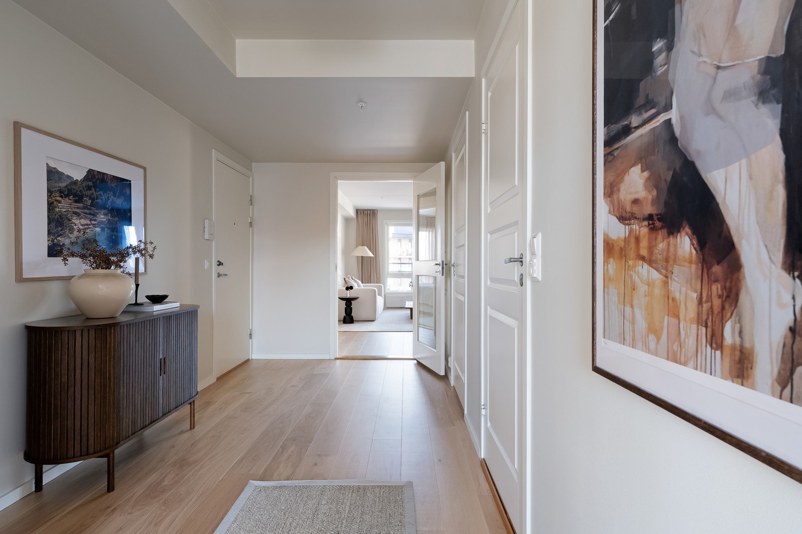 Innbydende entré med lyse overflater, praktisk planløsning, naturlig adkomst til flere rom og dørtelefon med åpner. Galleribilde