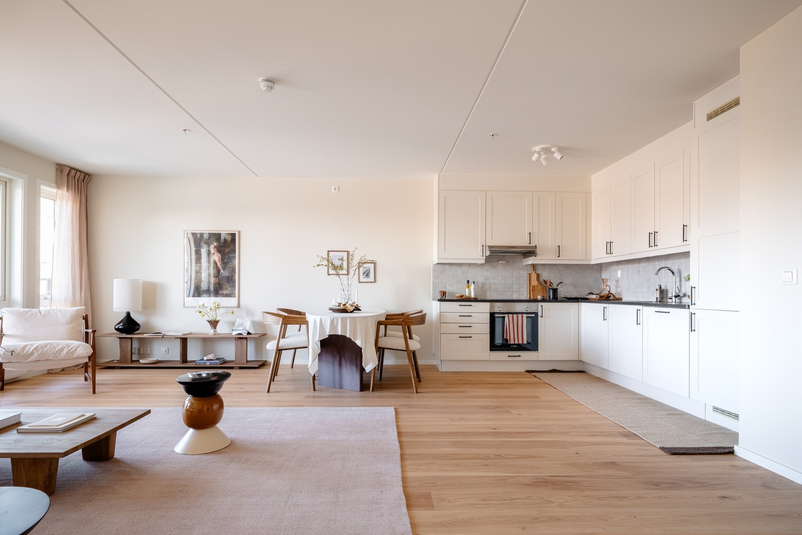 Stilrent Marbodal kjøkken i åpen løsning mot stuen, med rene linjer og gjennomtenkte materialvalg. Galleribilde