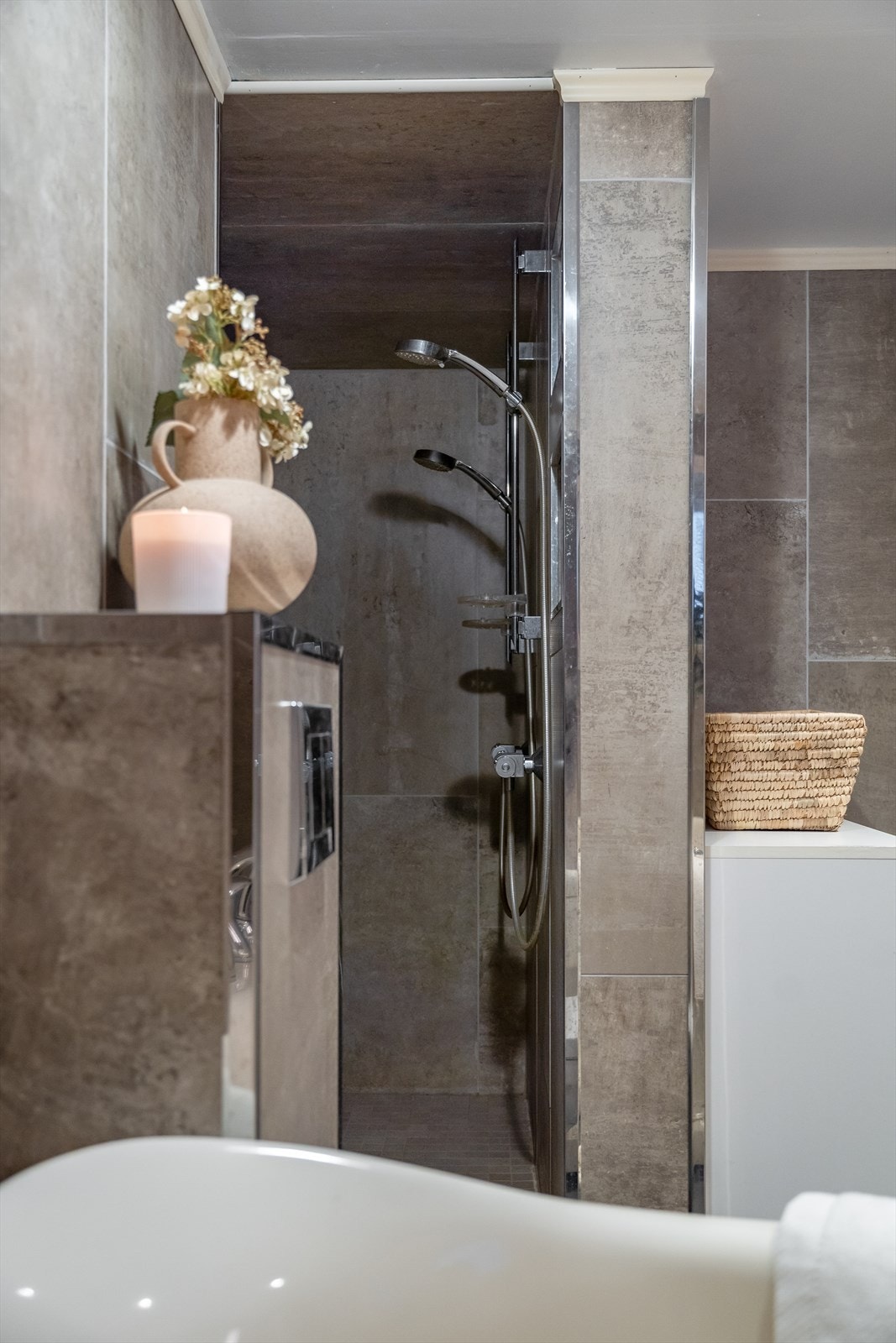 Lekkert dusjhjørne med dobbeldusj, mosaikkfliser og integrerte nisjehyller. Galleribilde