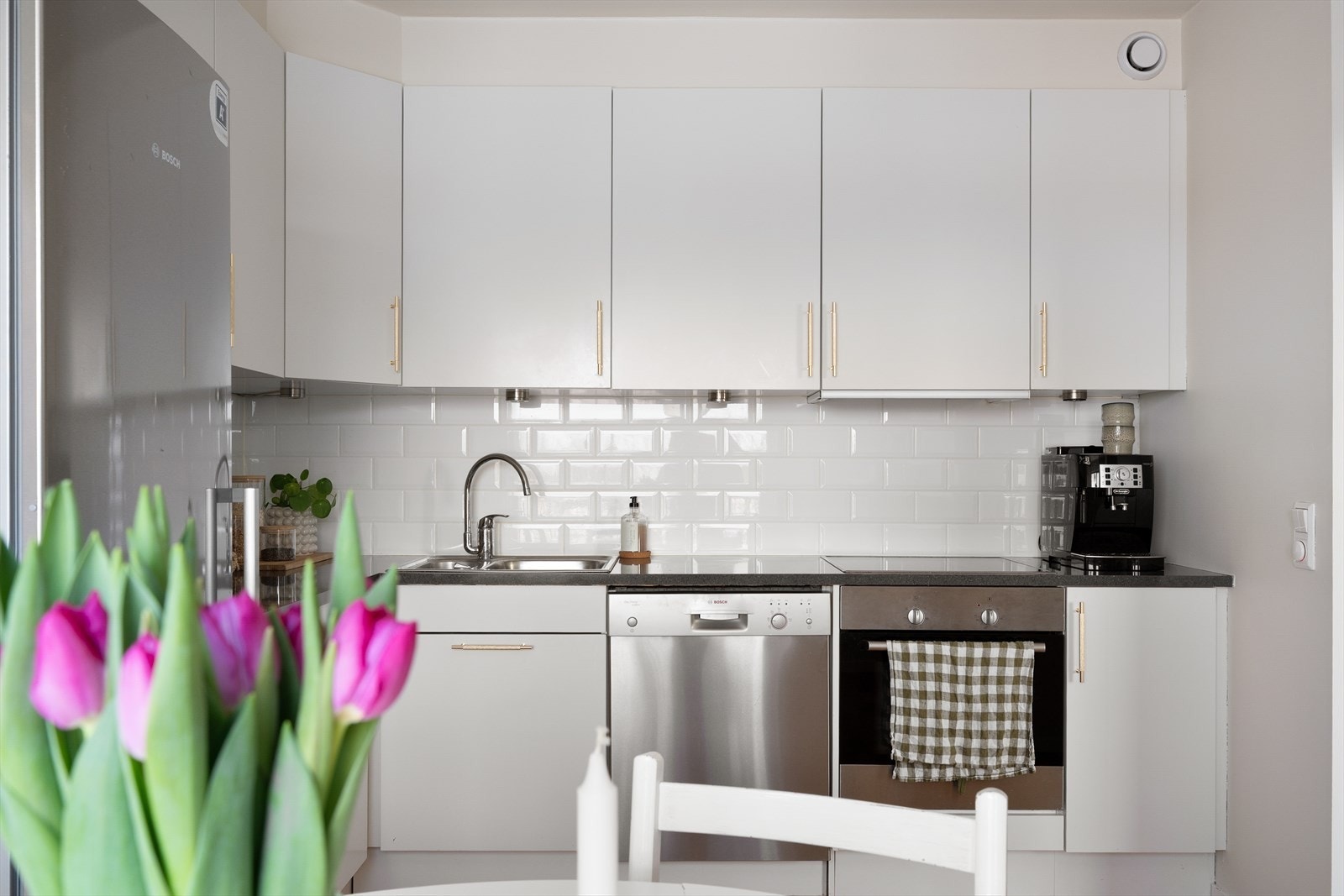 Stilrent kjøkken med lyse fronter og flislagt vegg. Galleribilde