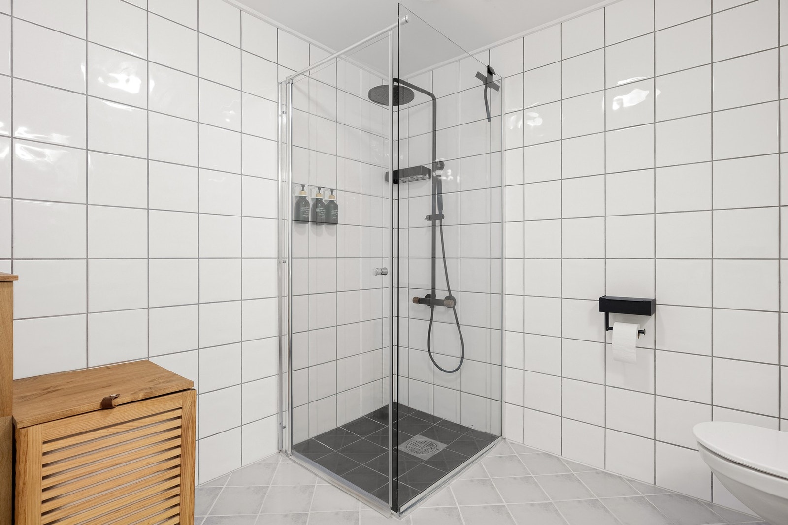 Det er innredet med vegghengt toalett, dusjgarnityr i dusjhjørne og baderomsinnredning med servant, speil og belysning. Galleribilde