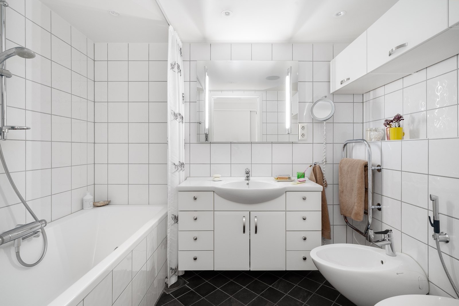 To lyse, flislagte bad med standard fra byggeår - en funksjonell løsning som gjør hverdagen enklere, enten man er flere i husstanden eller har gjester på besøk. Galleribilde