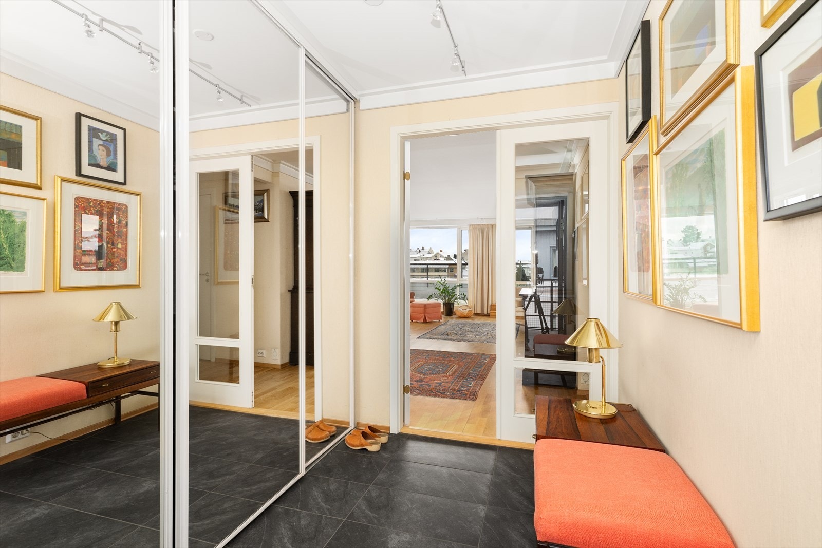 Romslig hall med flislagt gulv, varmekabler og dobbel innerdør med glassfelt til stuen. Stor, praktisk skyvedørsgarderobe for skjult oppbevaring av sko- og yttertøy. Galleribilde