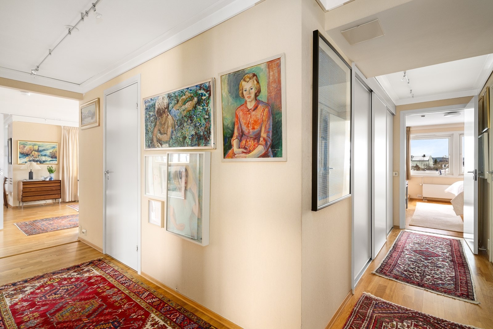 Romslig gangareal hvor det utenfor hovedsoverommet er etablert en stor og praktisk skyvedørsgarderobe med rikelig plass til klær og oppbevaring. Galleribilde