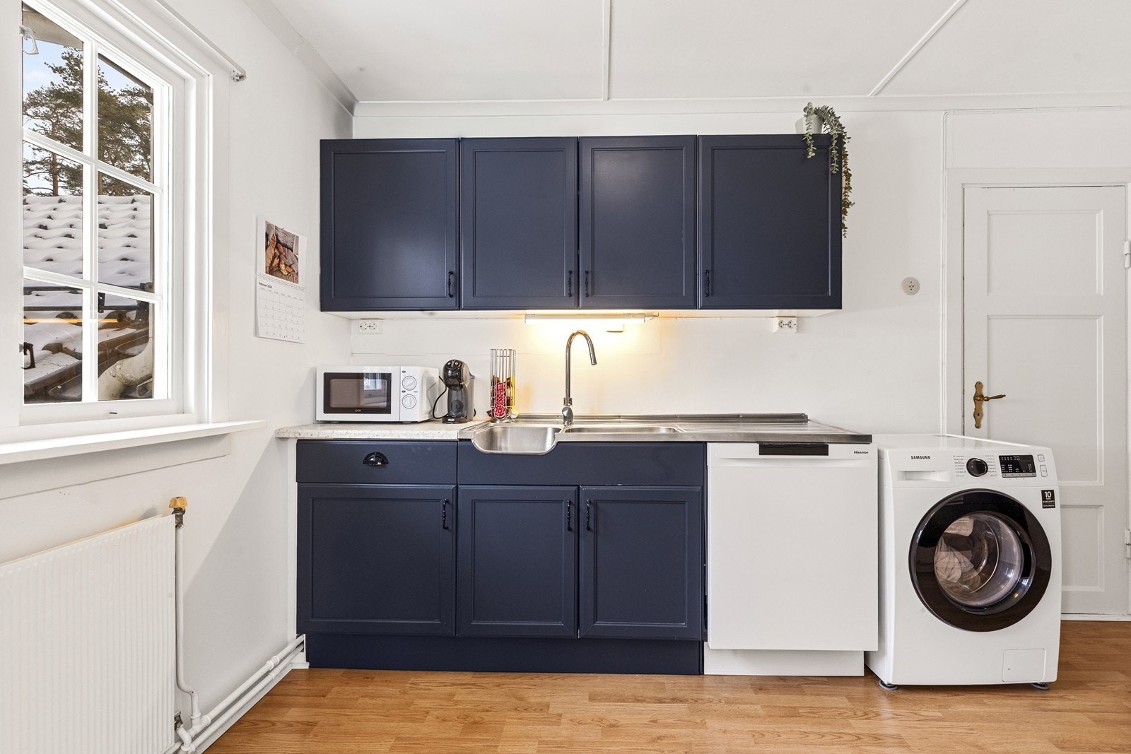 Kjøkkenet er funksjonelt innredet med laminatbenkeplate og opplegg for vaskemaskin. Galleribilde