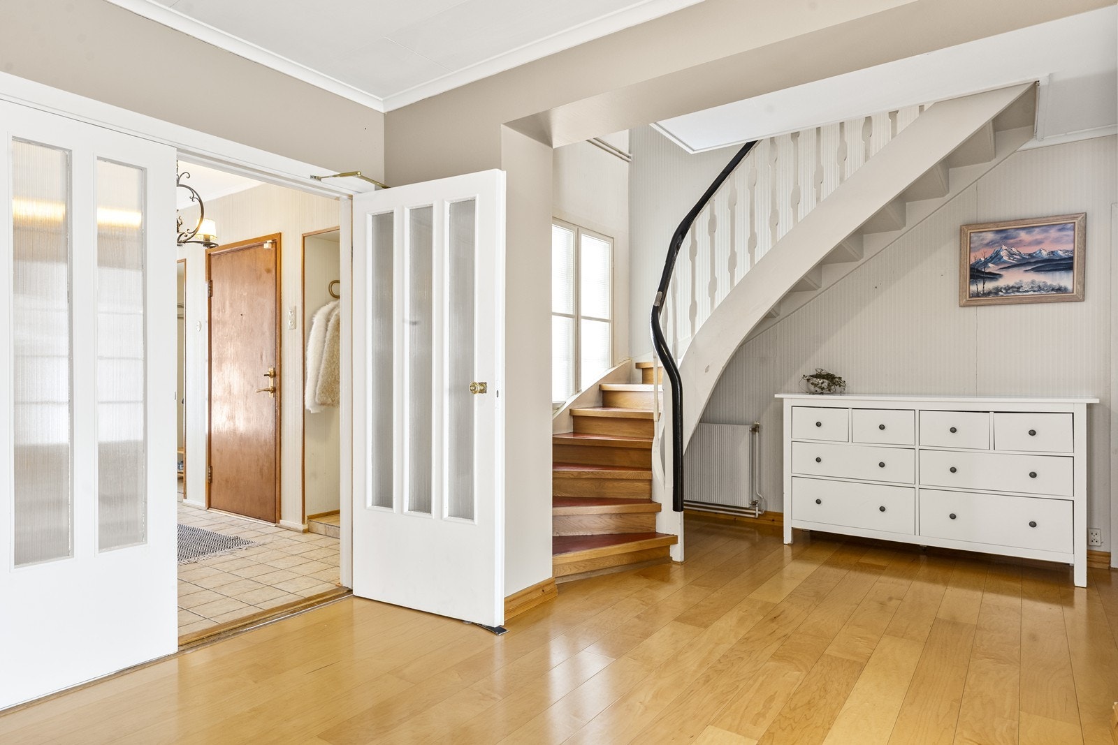 Hallen ønsker velkommen med parkettgulv og en elegant trapp som leder til andre etasje. Flislagt gulv med egen trapp i entréen. Galleribilde