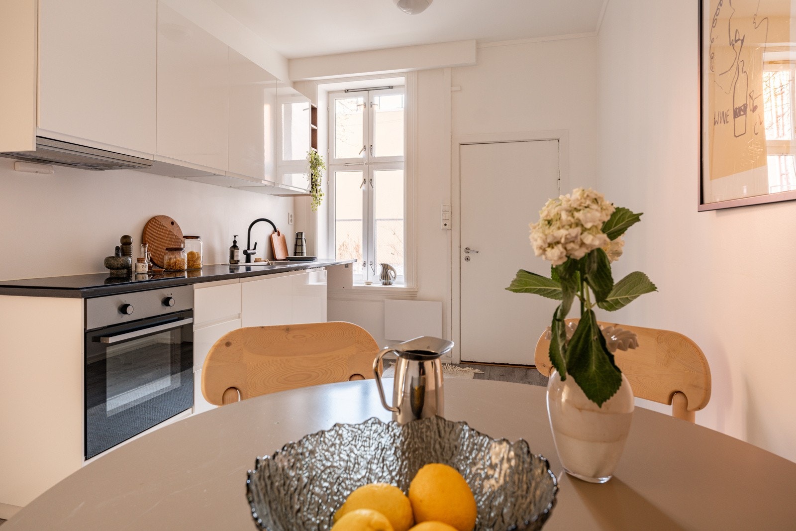 Kjøkkenet har enstavs laminat på gulv, glatte lysmalte overflater og et stort klassisk vindu. Galleribilde