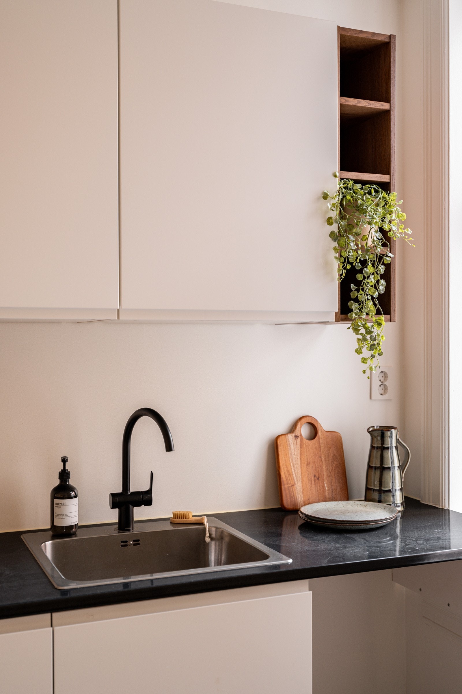 Kjøkkenet har stilrent sort armatur og flotte åpne hyller i treverk. Galleribilde