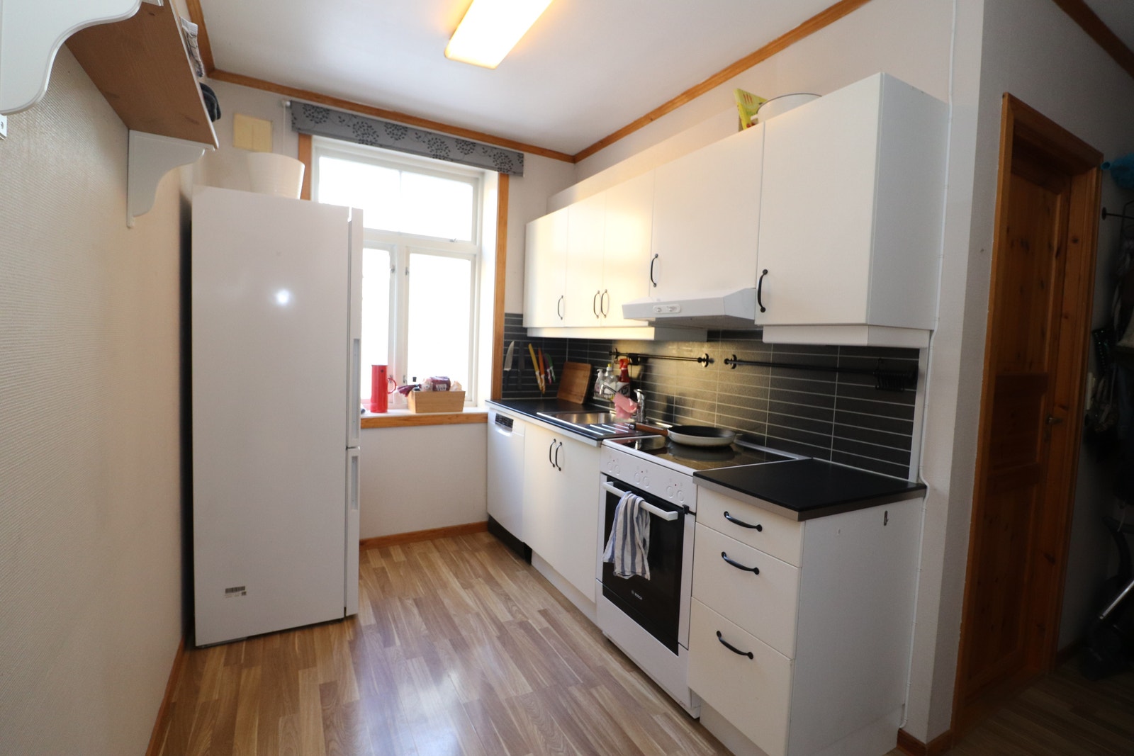 Kjøkken med kombiskap(kjøl/frys), komfyr og oppvaskmaskin Galleribilde