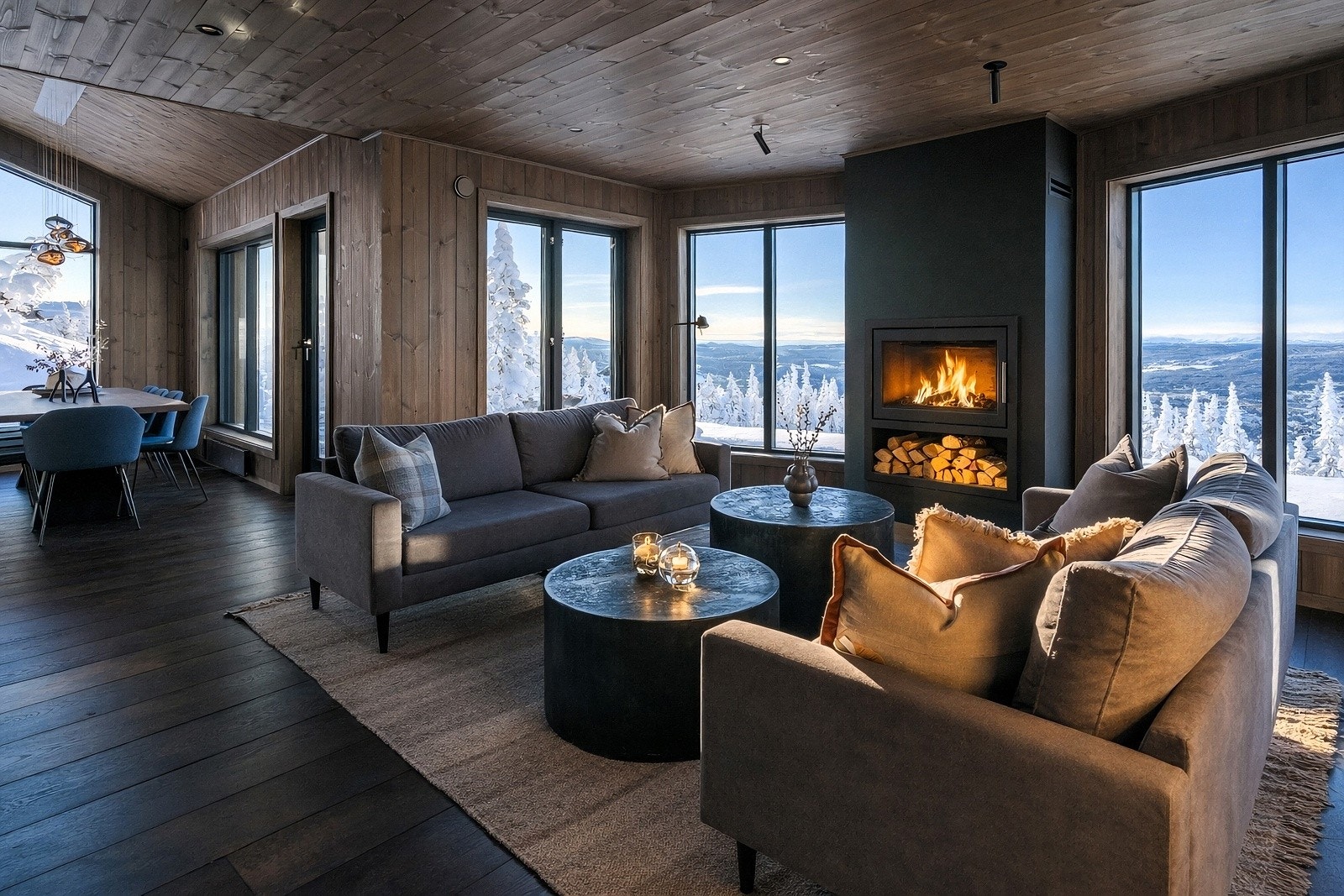 Velkommen inn! En av hyttas to stuer med store vinduer, peisinnsats og ferdig møblert sofagruppe Galleribilde