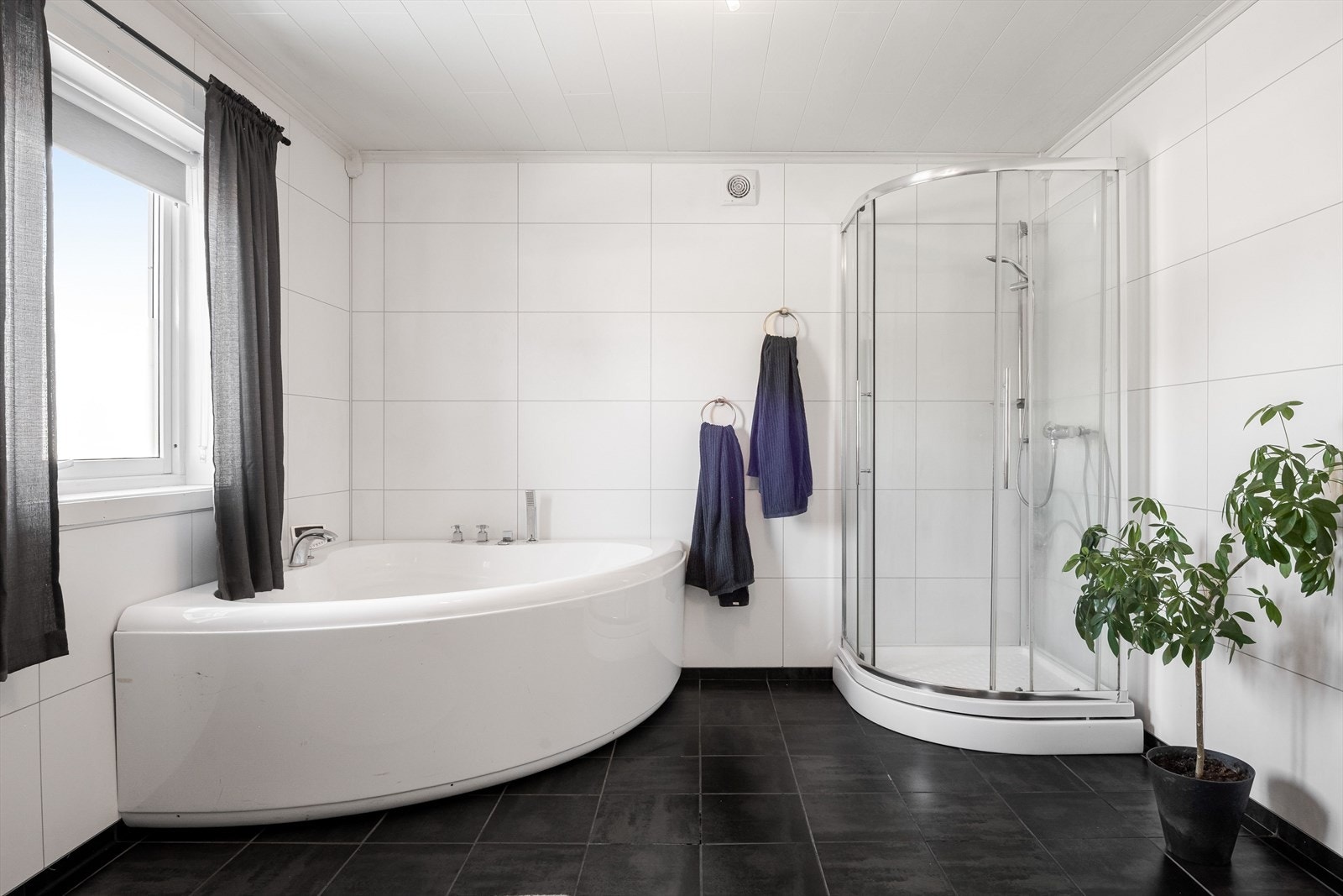 Flislagt baderom i 1.etasje med varmekabler i gulvet. Baderommet er innredet med toalett, servant på innredning, badekar og dusjkabinett. Galleribilde