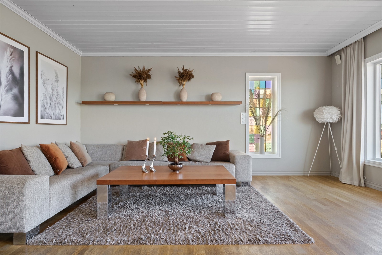 Stuen har parkettgulv, lysbeige, glatte veggflater og hvitmalt panelhimling med bjelker. Galleribilde