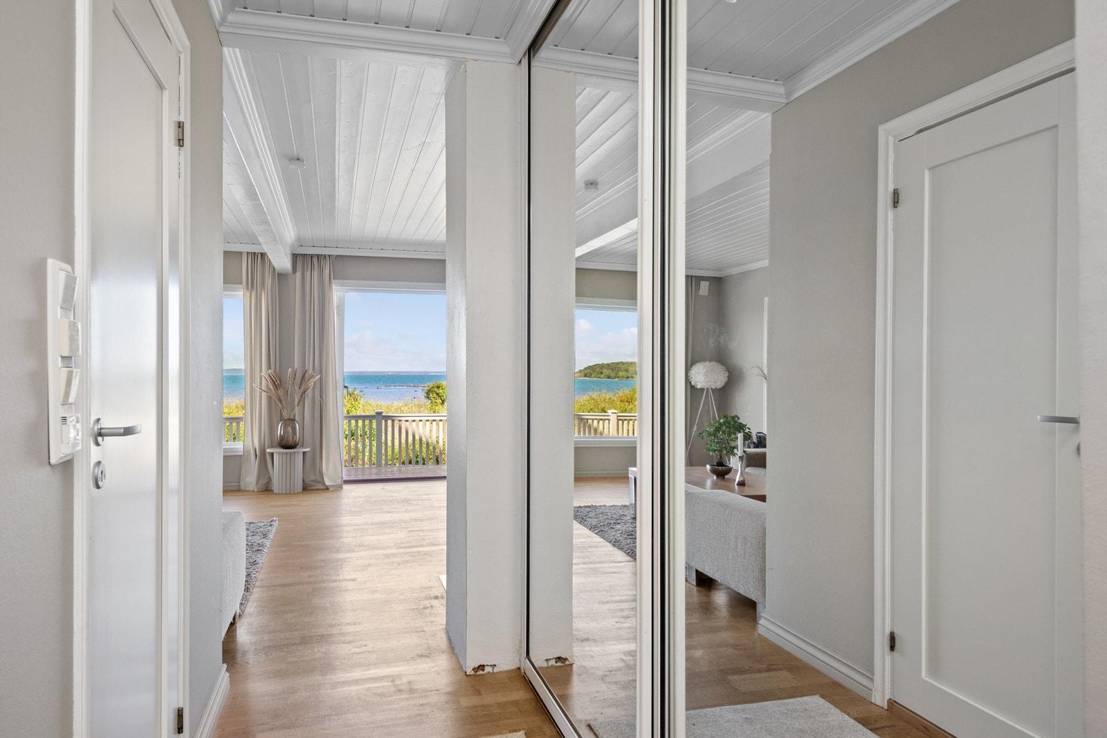 Entreen ligger åpen mot stuen, slik at det første man ser er den nydelige sjøutsikten via store stuevinduer. Entreen har også en stor skyvedørsgarderobe med speilfronter langs den ene siden og inngang til badet på den andre. Galleribilde