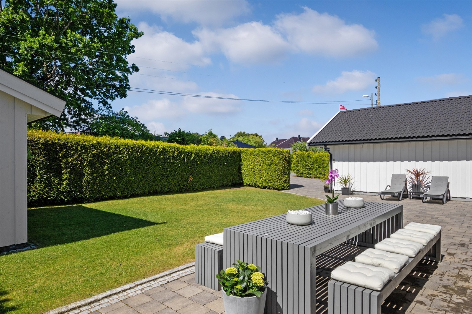 Tomten er pent opparbeidet med velstelte plenarealer, rammet inn av tettvokst og velfrisert hekk. Galleribilde