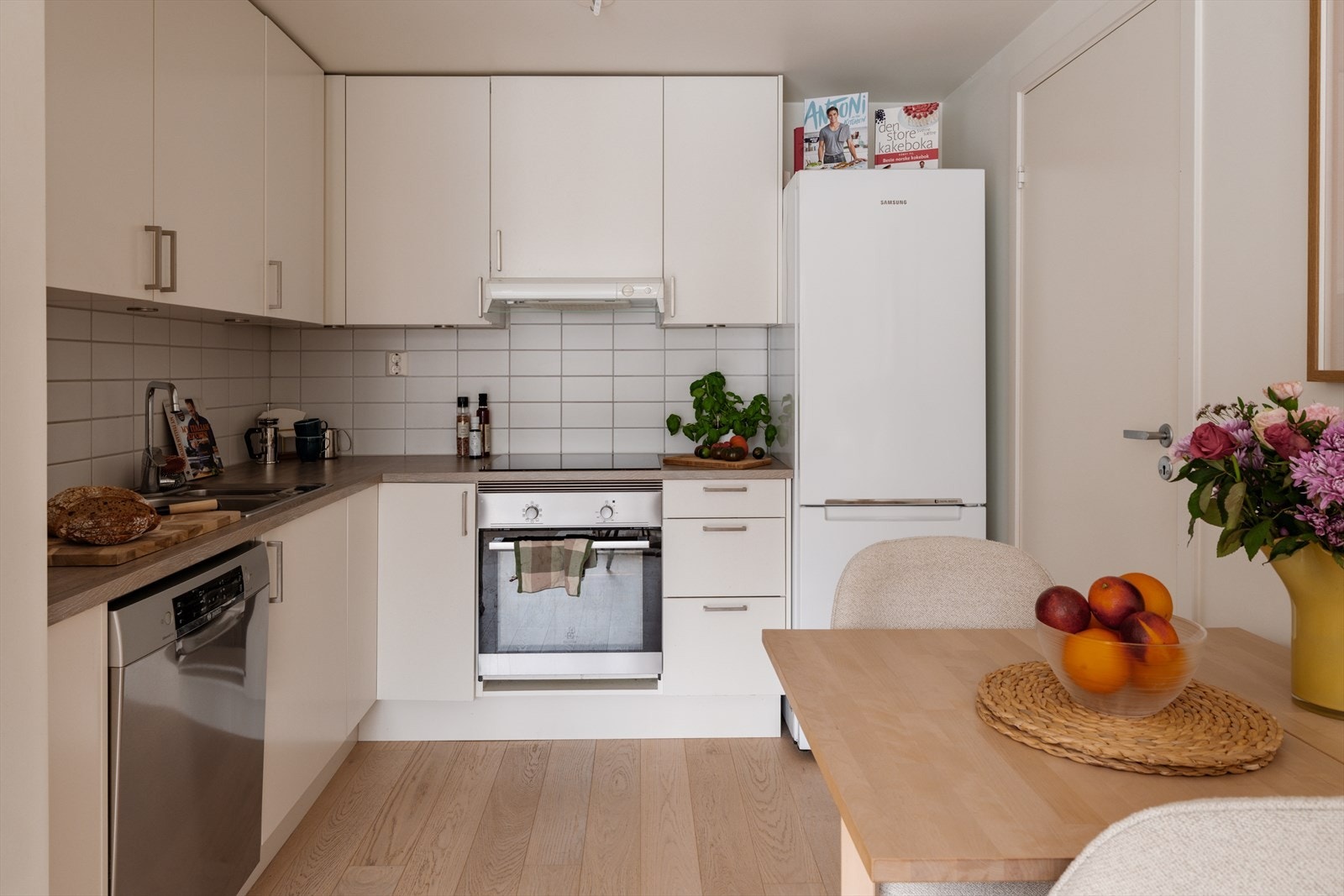 Lyst, tidløst kjøkken med plass til spisebord mellom sonene. Galleribilde