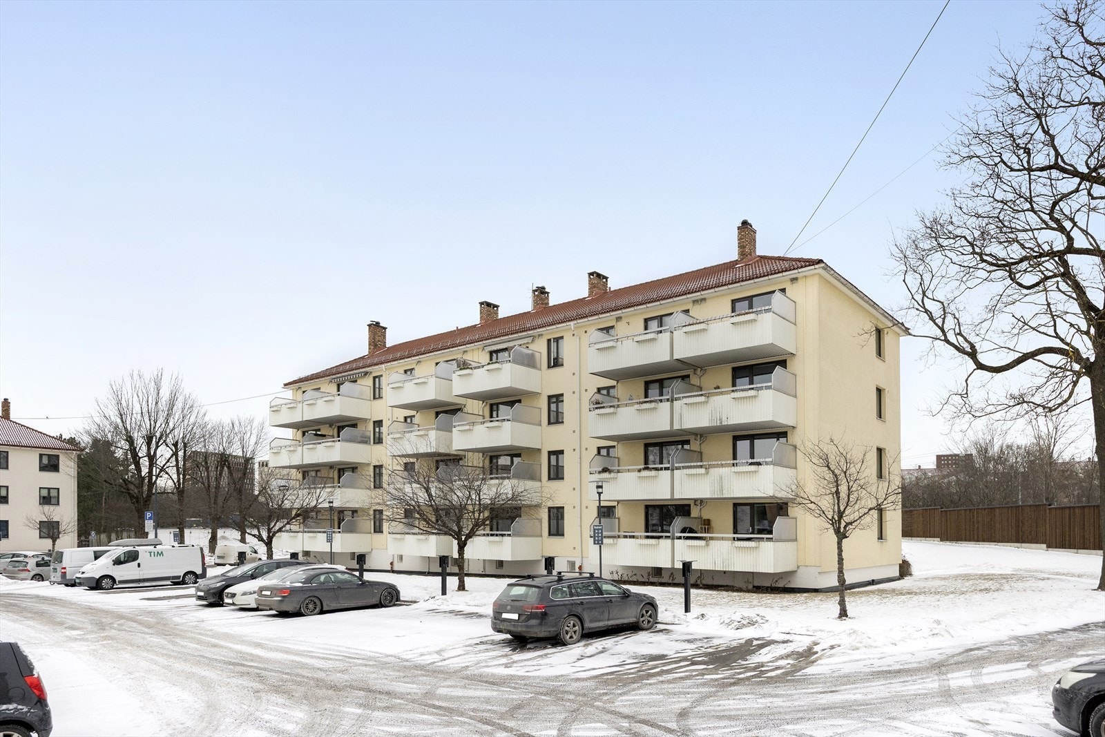 Byggets fasade med flere balkonger - klassisk blokkbebyggelse og ryddige adkomstforhold rundt bygget. Galleribilde