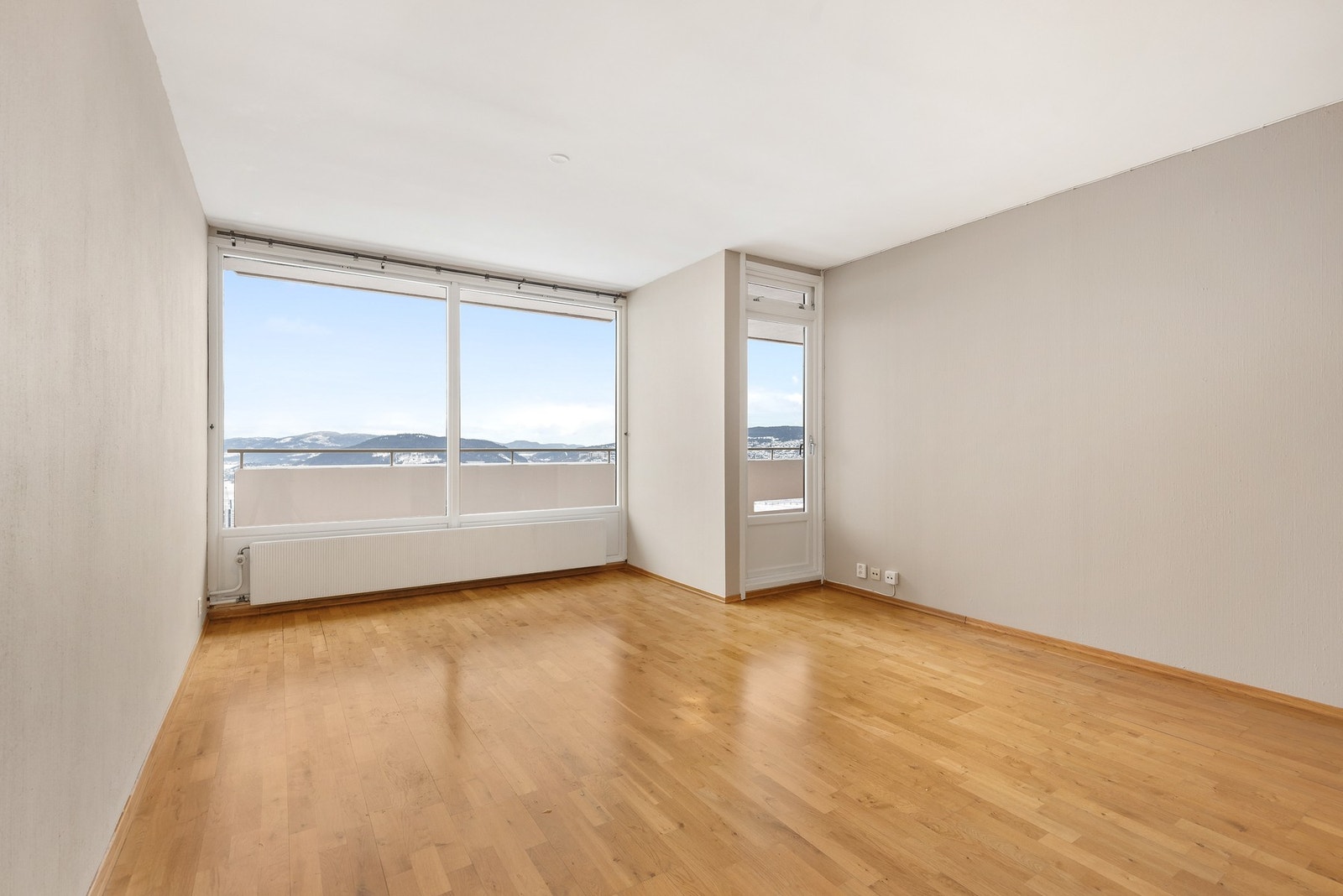 Lys stue med parkettgulv, malt strietapet på vegger og malt betong i himling Galleribilde