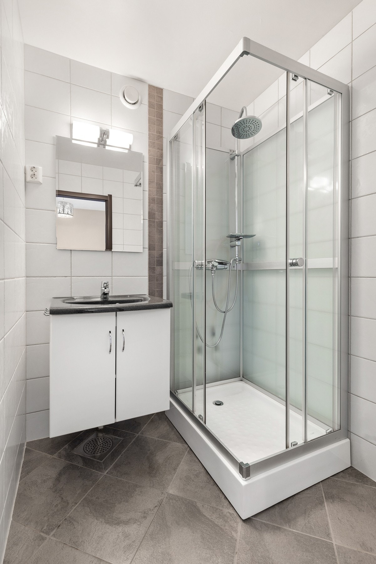 Badet er innredet med dusjkabinett, servantinnredning og speil. Det er mekanisk avtrekk Galleribilde