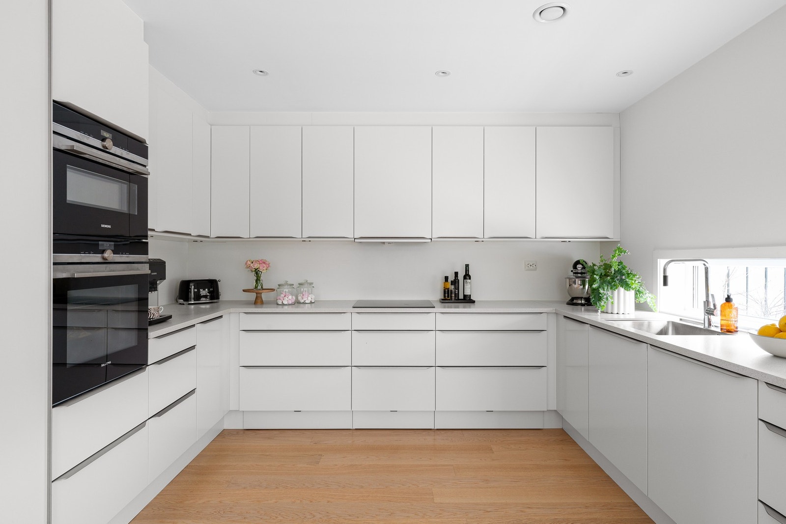 Kjøkkenet har slette hvite fronter som gir et minimalistisk og tidløst uttrykk. Benkeplaten er i laminat. Galleribilde