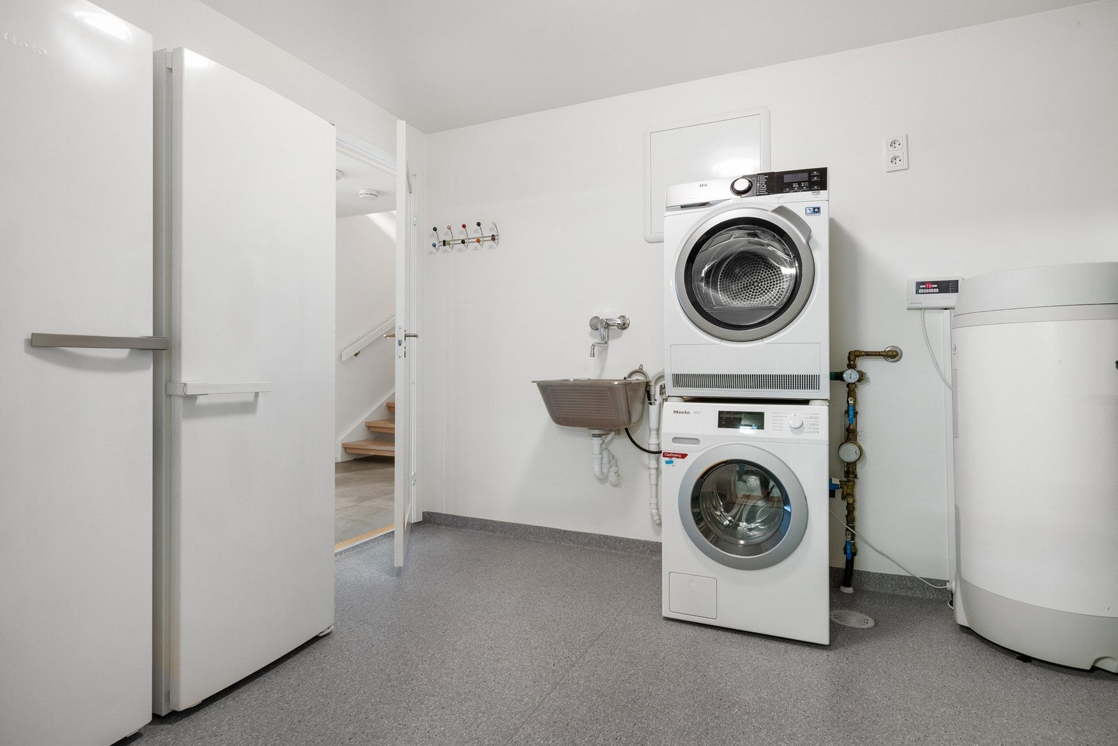Boligen har et praktisk vaskerom med belegg på gulv og malte overflater på vegger. Galleribilde